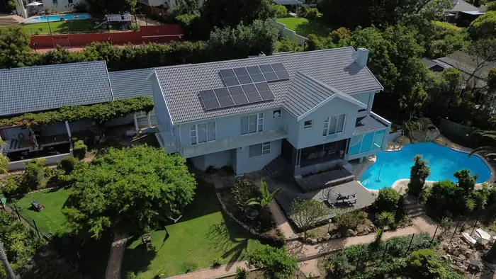 The house, lawn and pool seen from higher up, the garden grown in