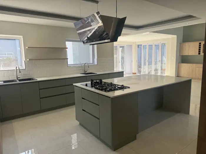 The kitchen island with stone top and extractor above