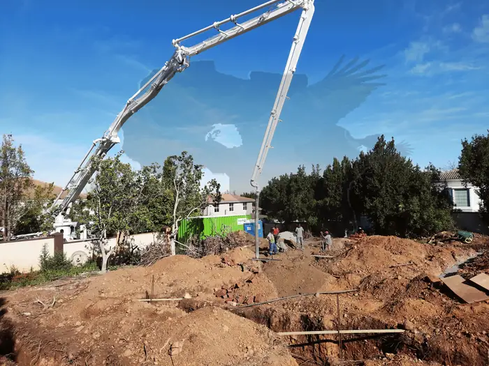 A concrete pump reaching over the foundations at House Hillcrest