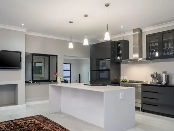 The finished kitchen at House Hillcrest with a stone island and dark cabinetry