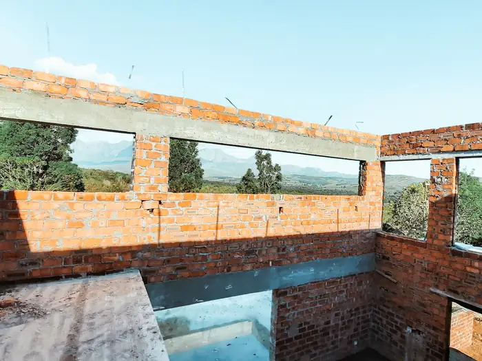 Long window openings left in the brickwork at House Hillcrest, framing the mountains beyond