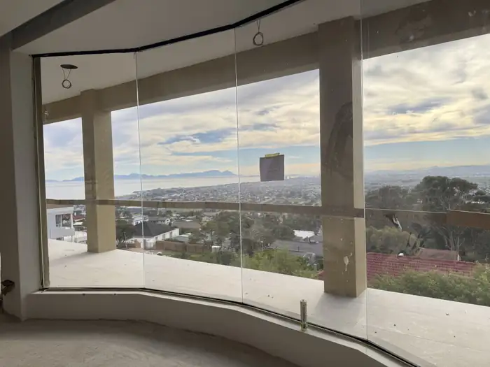 Frameless glass balustrade on the terrace with the bay and mountains beyond