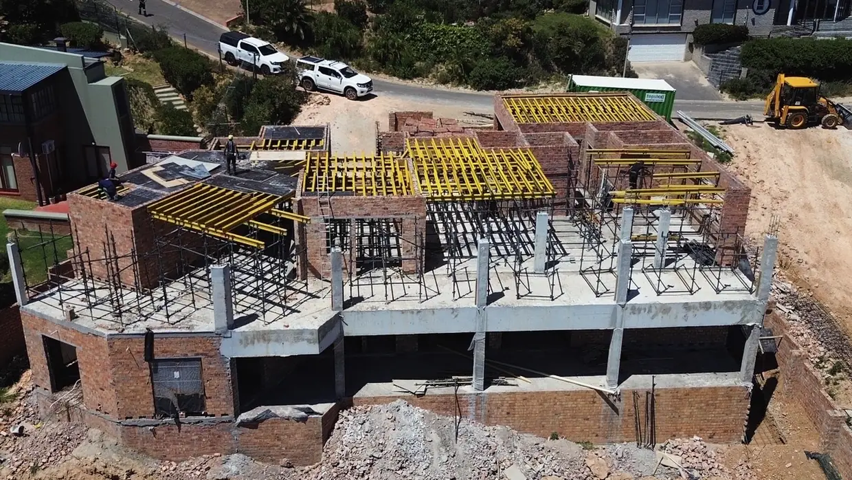 House Makhene under construction: reinforcing tied, columns cast, and yellow formwork propping the next slab
