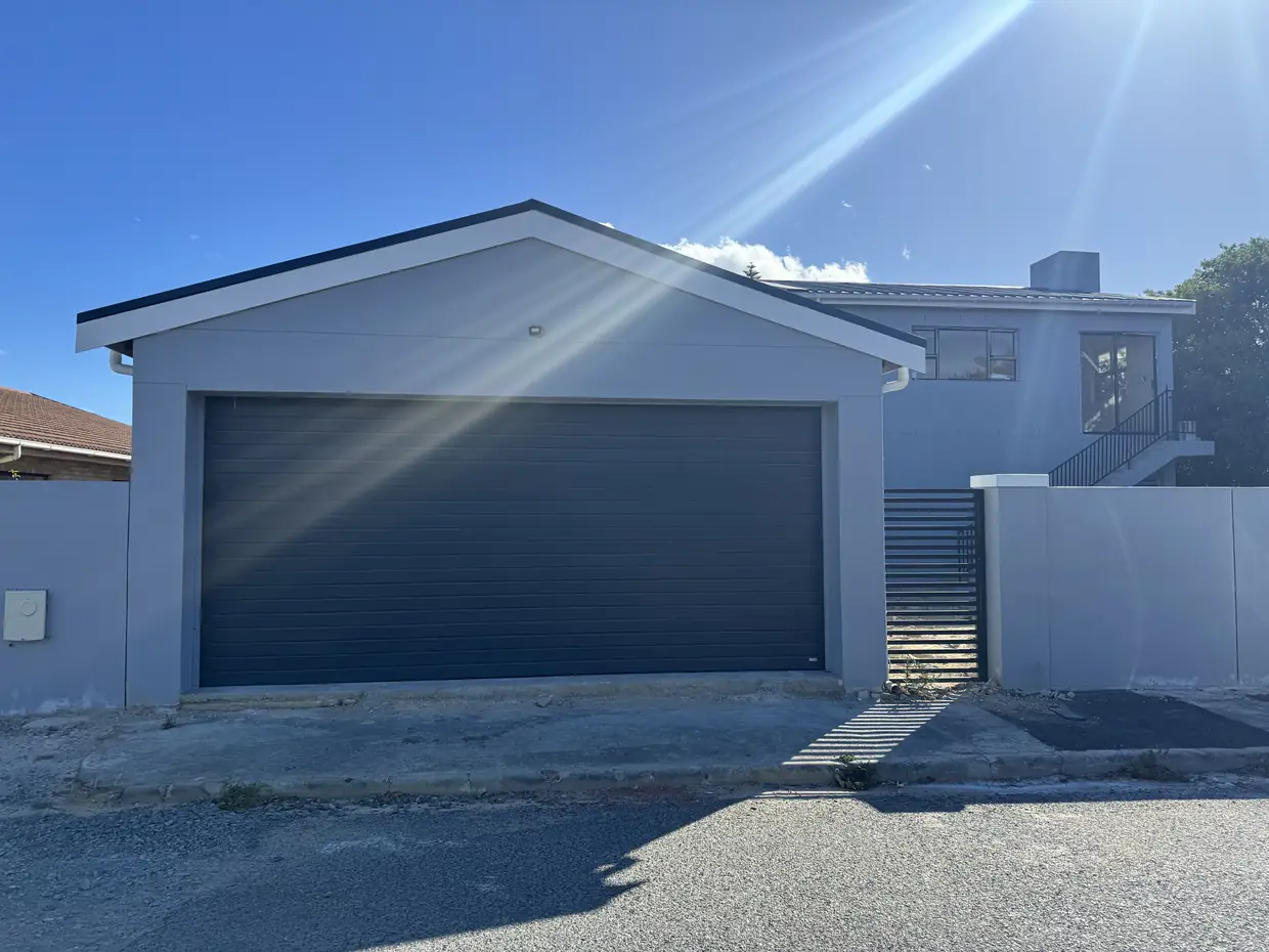 The Marais Street house in Strand seen from the road, the double garage under its gable with the upper floor behind