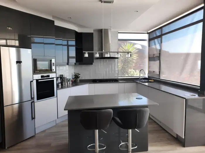 The kitchen with built-in appliances and a stone topped island