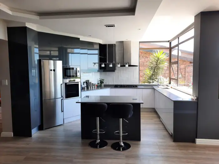 The kitchen island and bar stools under the corner glazing