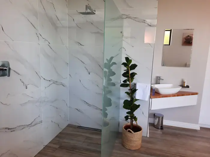 A frameless glass walk-in shower tiled floor to ceiling